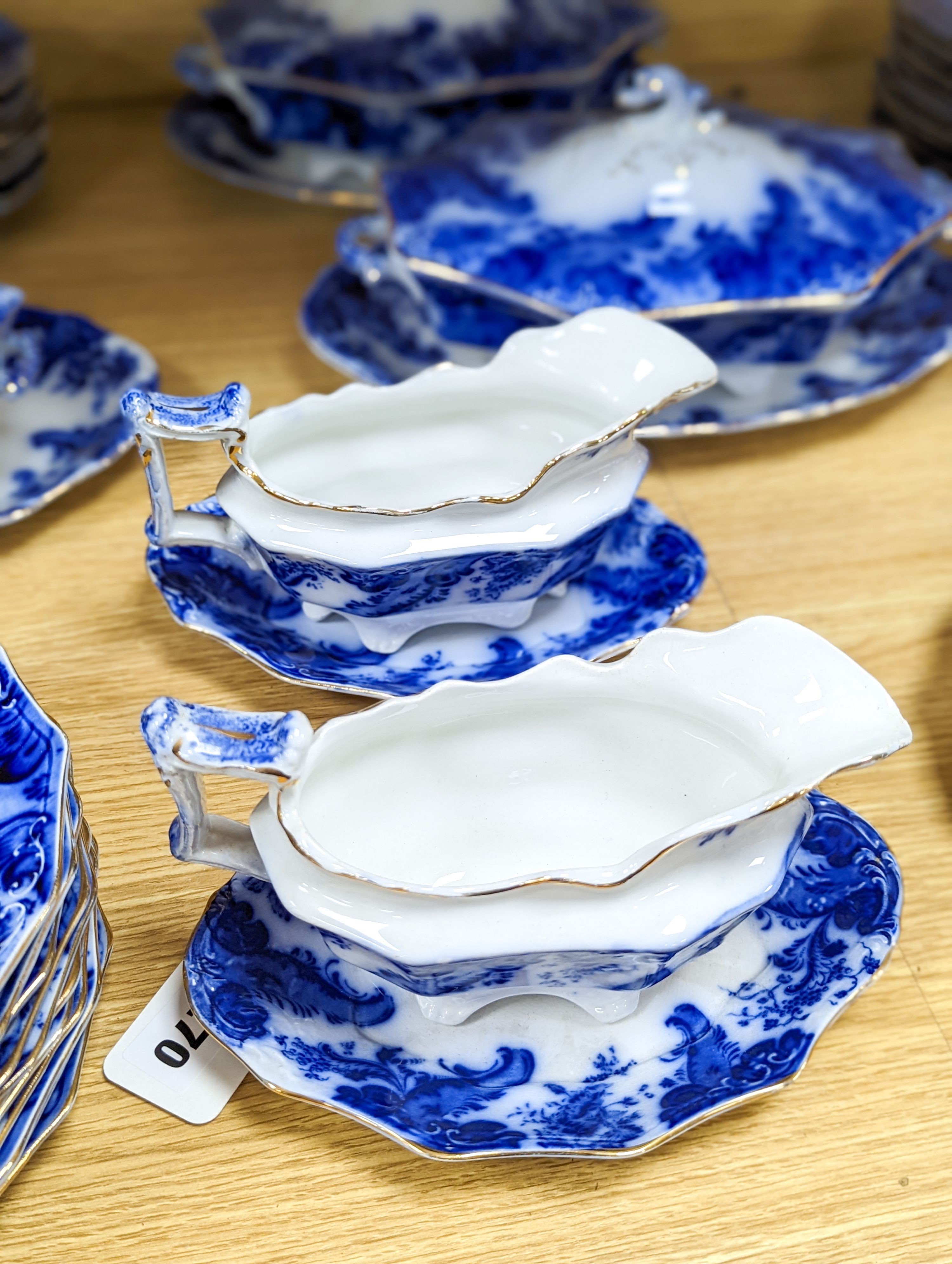 A W. H. Grindley Argyle pattern flow blue dinner service, c.1900 mostly for 12 place settings, two sauce tureens, covers and stands, two vegetable tureens and covers, two gravy boats, and six graduated meat dishes
